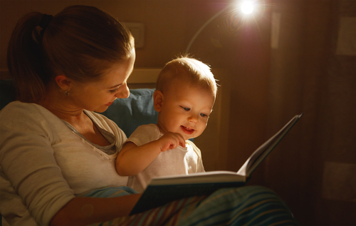 woman reading to baby in dimly lit room